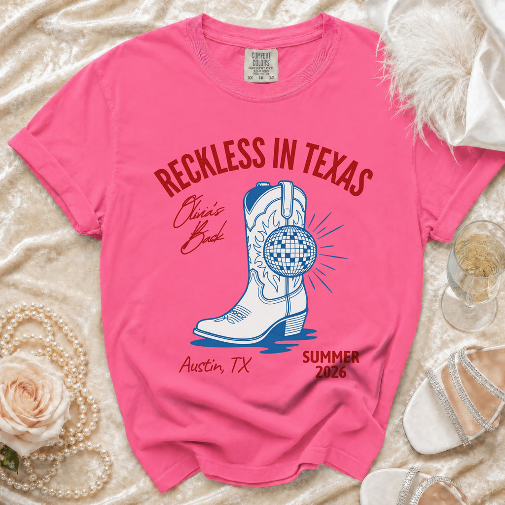 Pink t-shirt with "Reckless in Texas" and cowboy boot design.