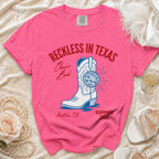 Pink t-shirt with "Reckless in Texas" and cowboy boot design.