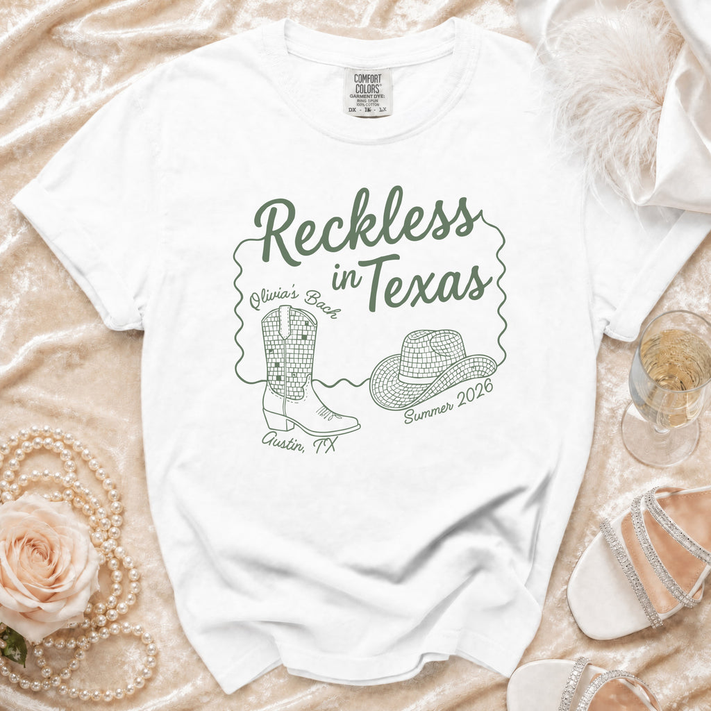 White t-shirt with "Reckless in Texas" text, cowboy boots, and hat graphic.