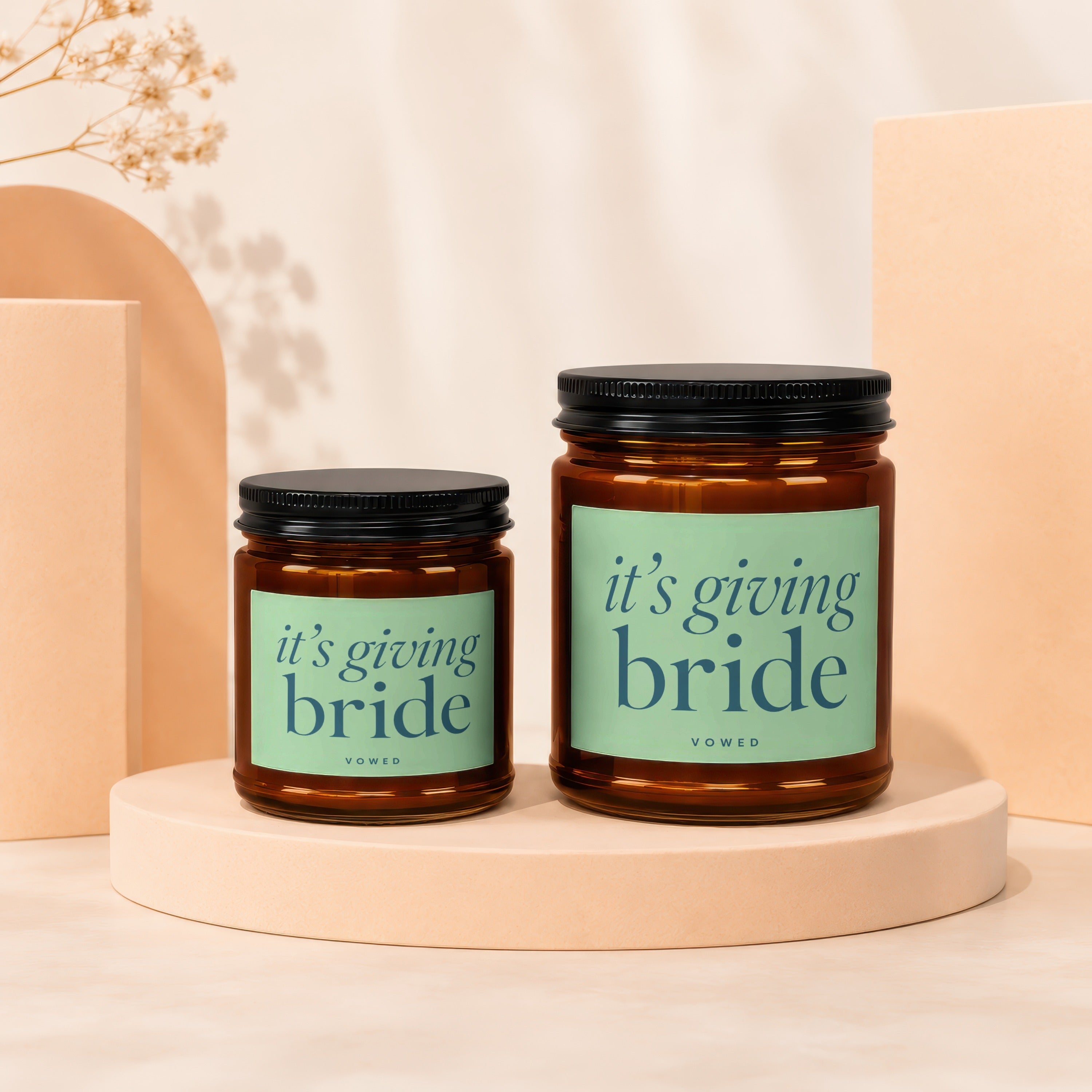 Two amber glass candles with black lids, one smaller than the other.