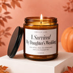 Amber jar candle with lit wick reads "I Survived My Daughter's Wedding."