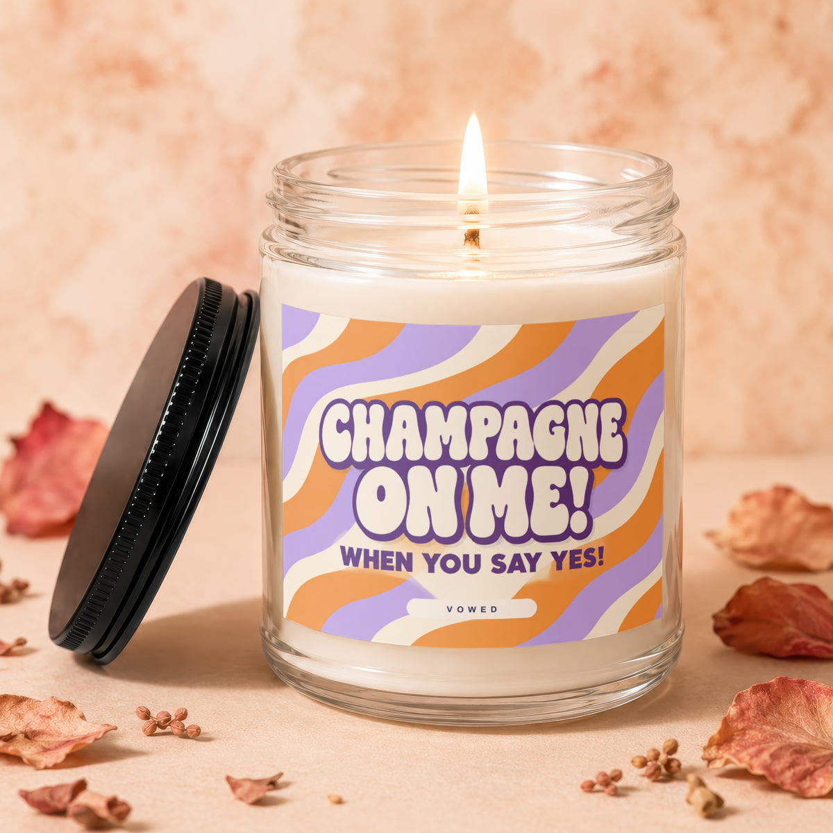 Candle with "Champagne on Me! When You Say Yes!" text on label, lid off.