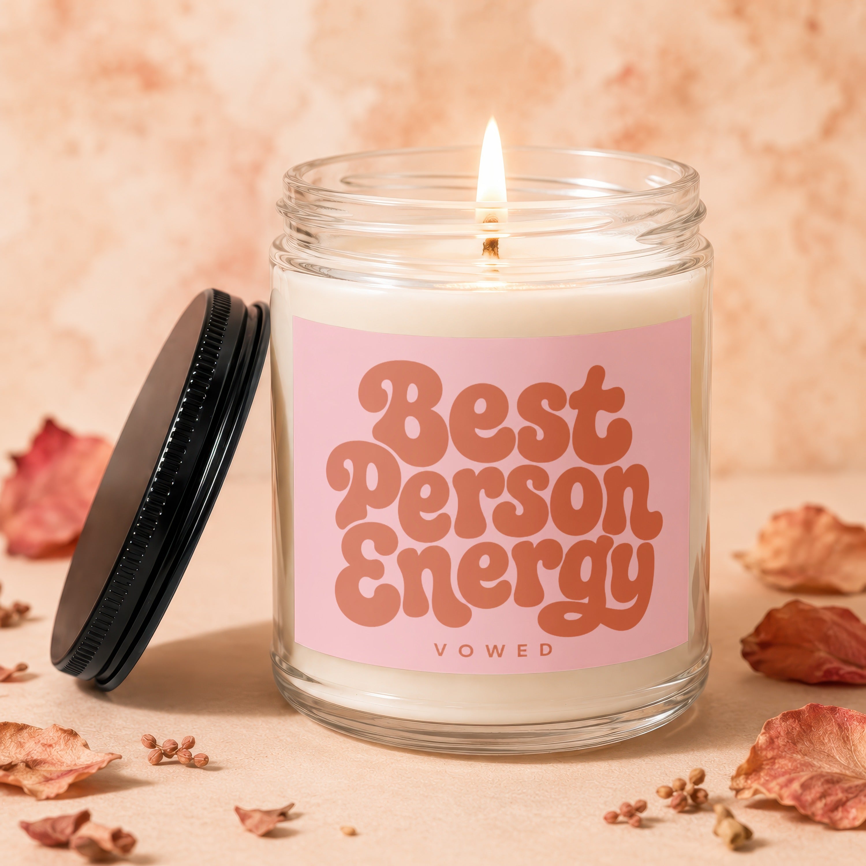 Glass candle with pink label reading "Best Person Energy" and a lit wick.