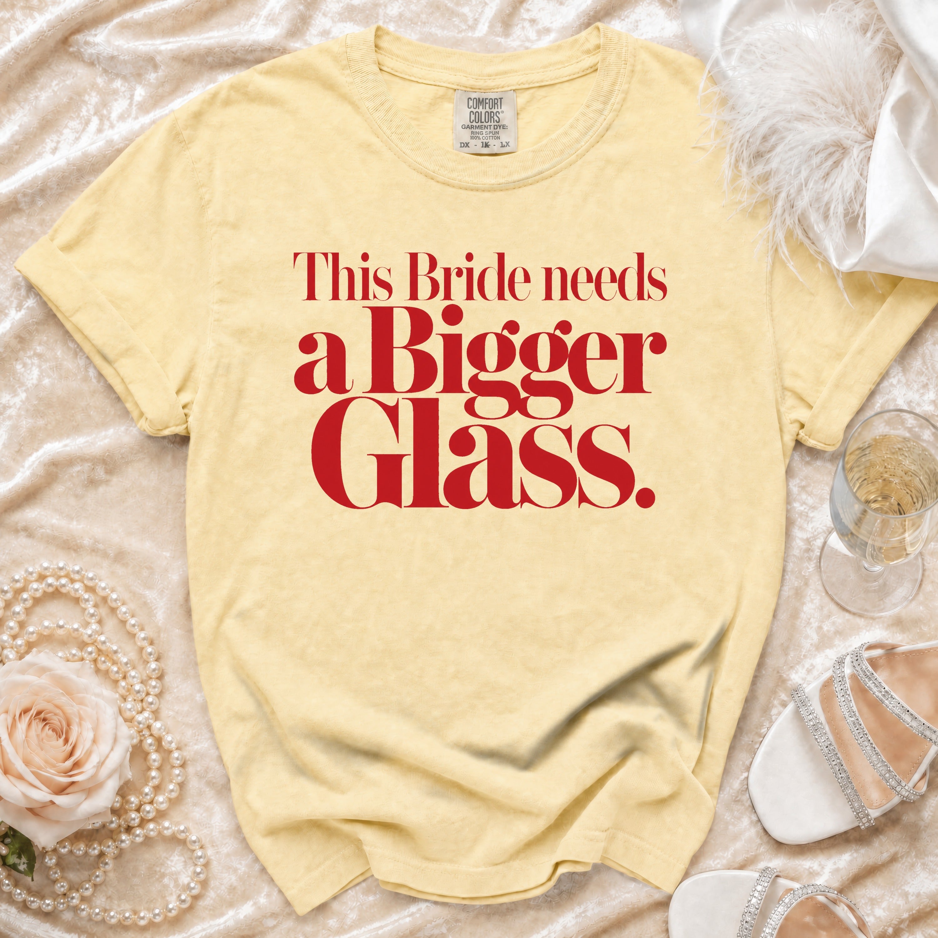Yellow t-shirt with red text that reads "This Bride needs a Bigger Glass."
