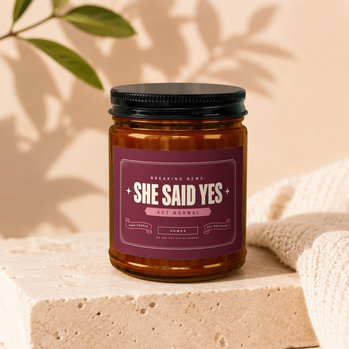 Amber jar candle with "She Said Yes" label, "Act Normal" subtitle, and "Vowed" text.
