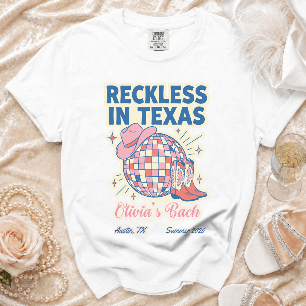 White t-shirt with "Reckless in Texas" and "Olivia's Bach" text and disco ball design.
