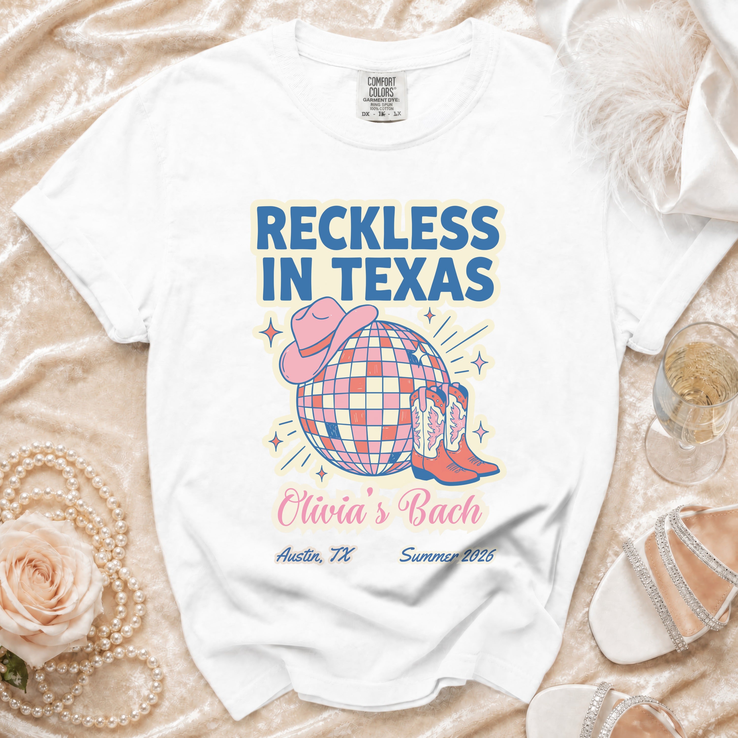 White t-shirt with "Reckless in Texas" and "Olivia's Bach" text and disco ball design.