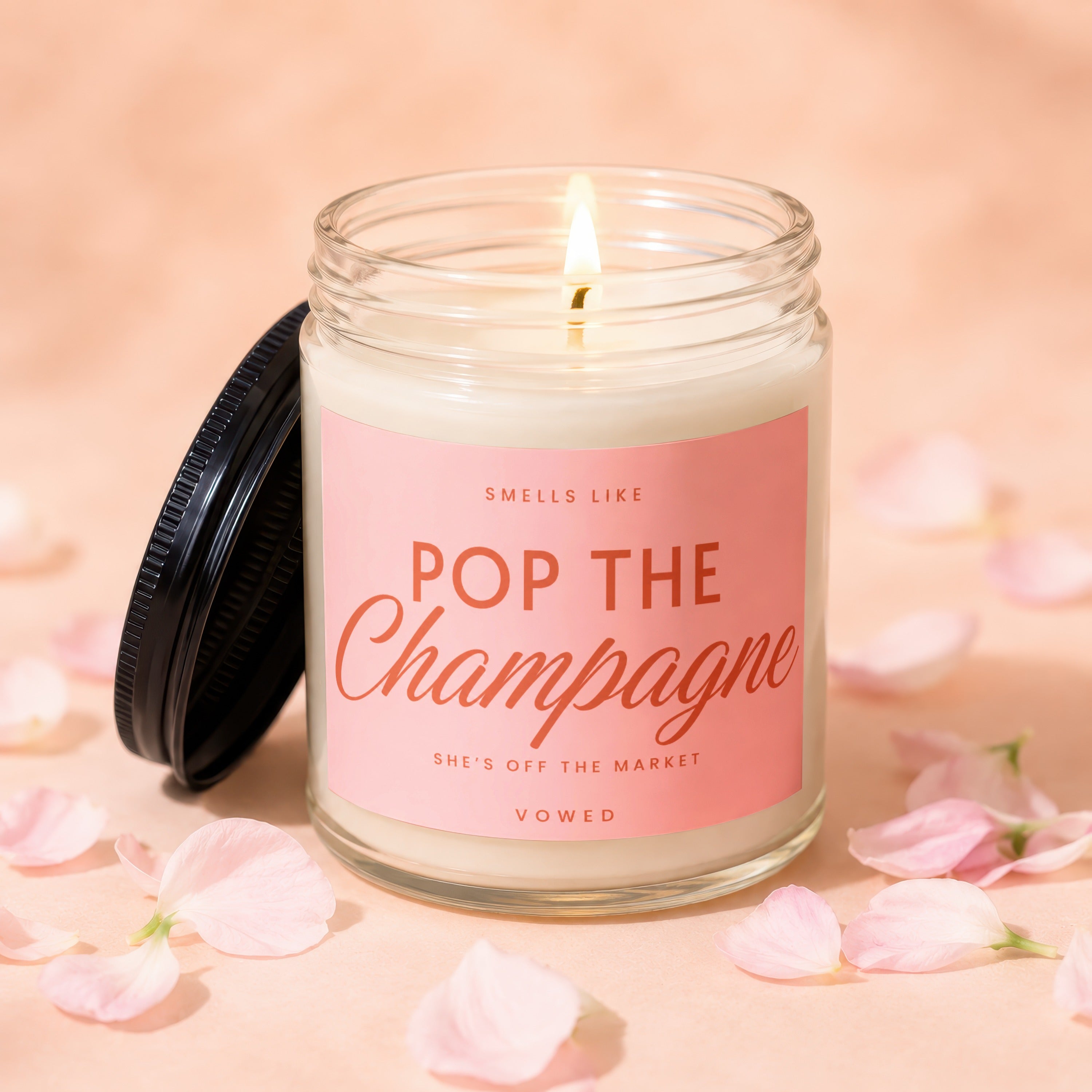 Soy candle with pink label reading "Pop the Champagne" and "She's Off The Market".