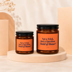 Two amber glass candles with orange labels asking "Not a Trick. Just a Question: Maid of Honor?".