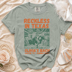 T-shirt graphic featuring a bull rider with "Reckless in Texas" and "Olivia's Bach" text.