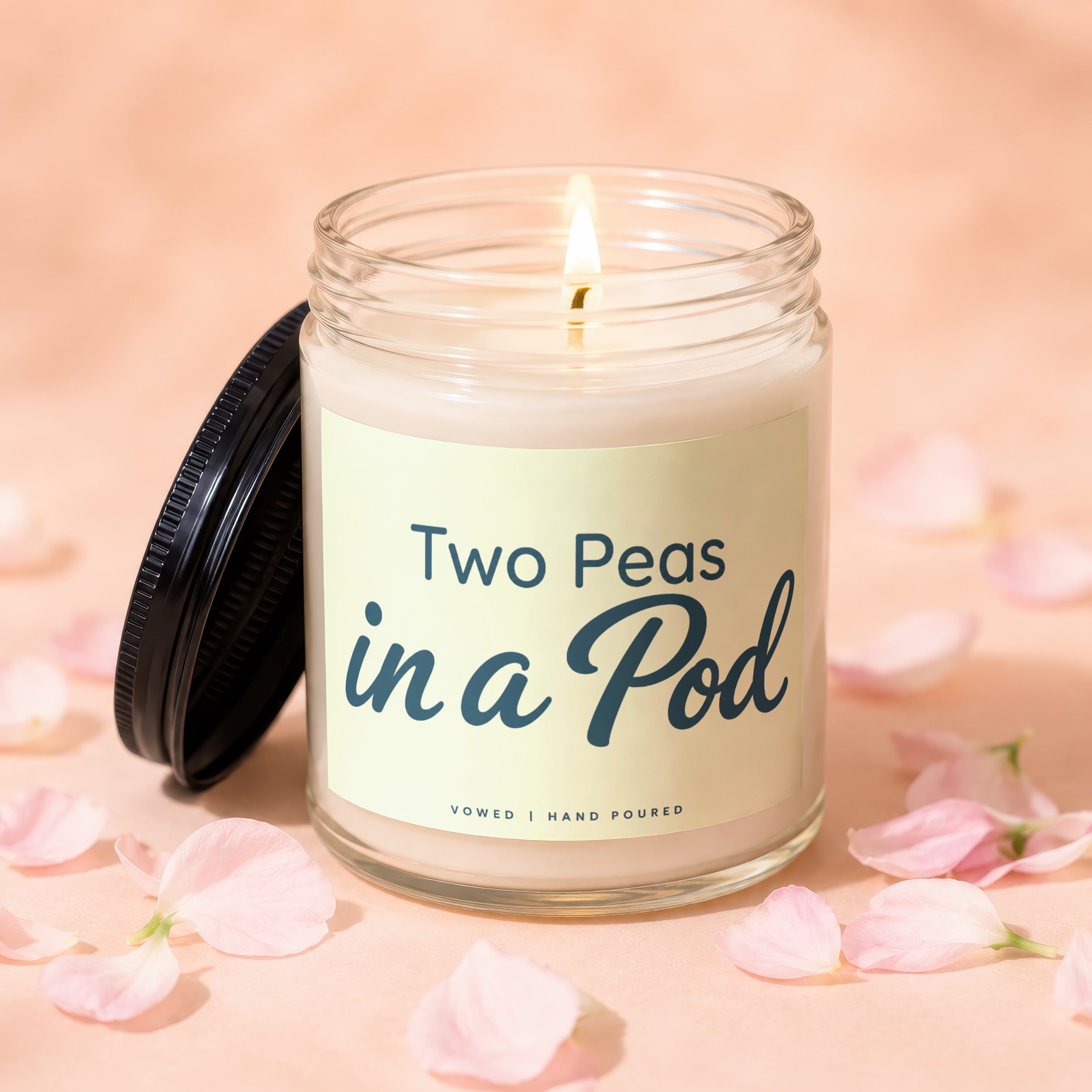 Lit candle in a glass jar with "Two Peas in a Pod" text and black lid.