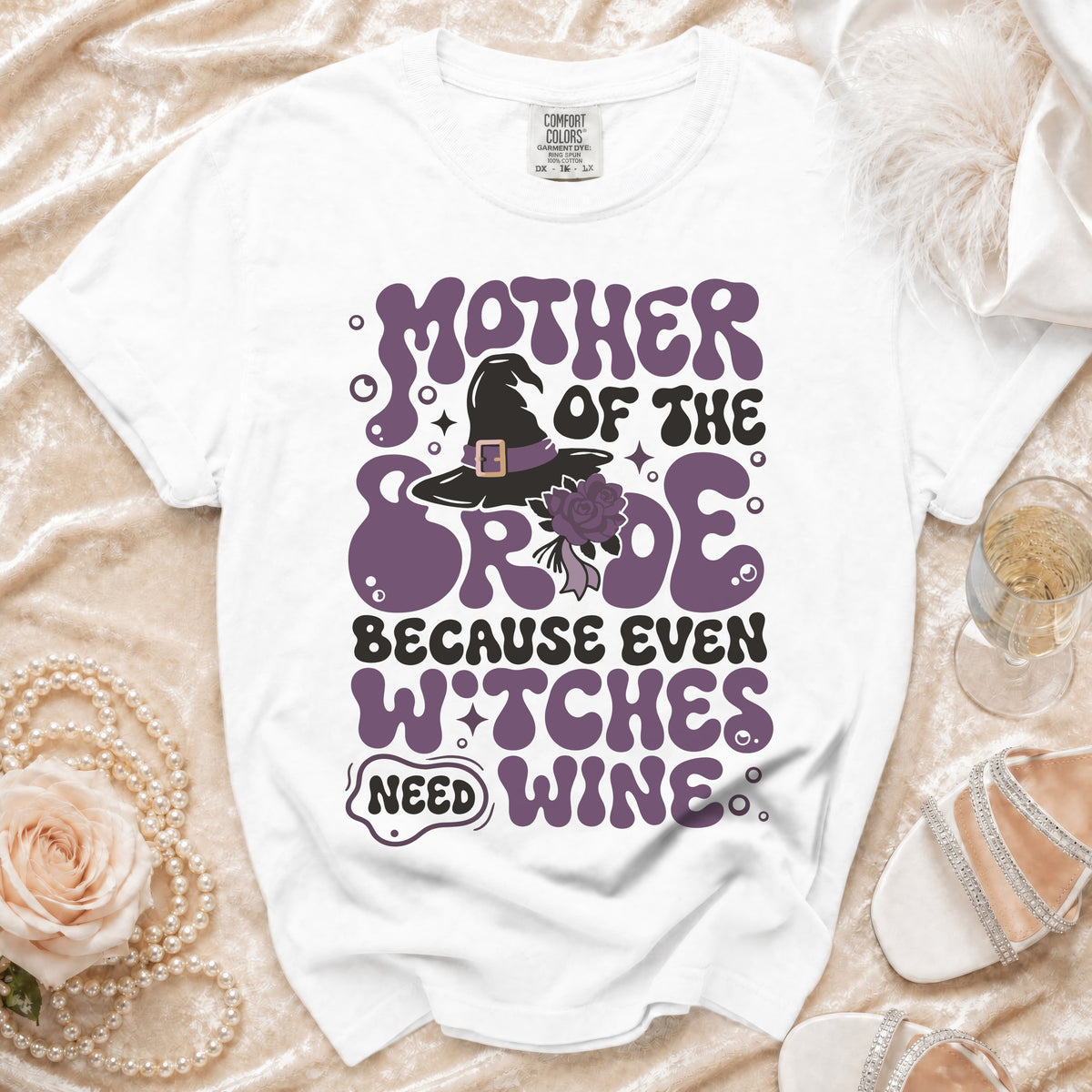 White t-shirt with purple graphic: Mother of the Bride Because Even Witches Need Wine.