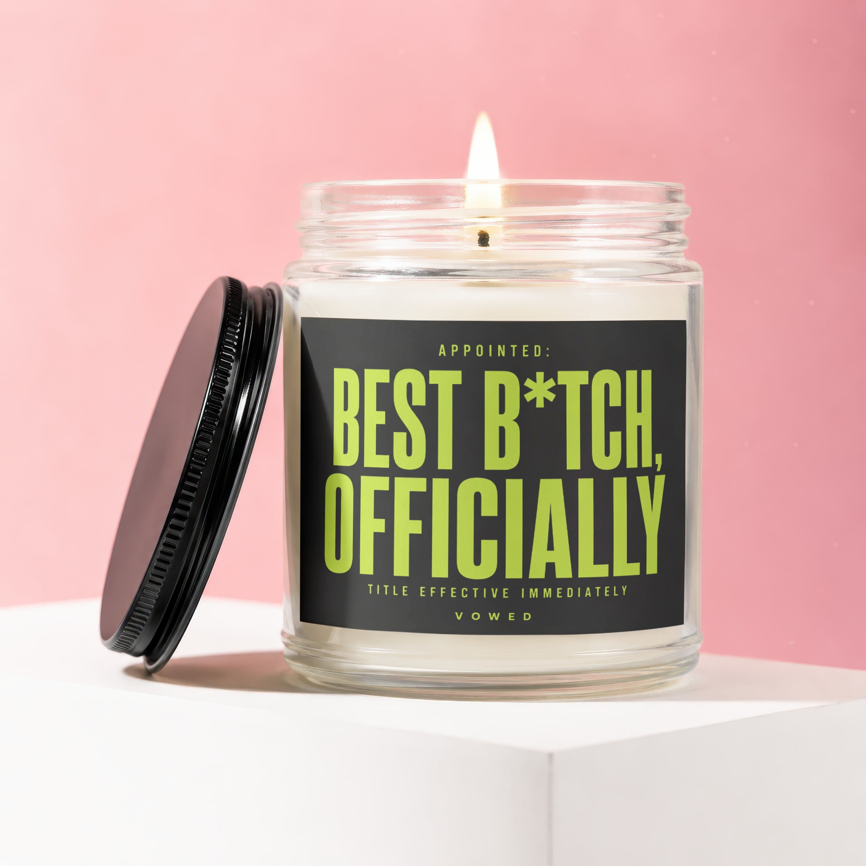"Appointed: Best B*tch, Officially" candle with lit wick and black lid.