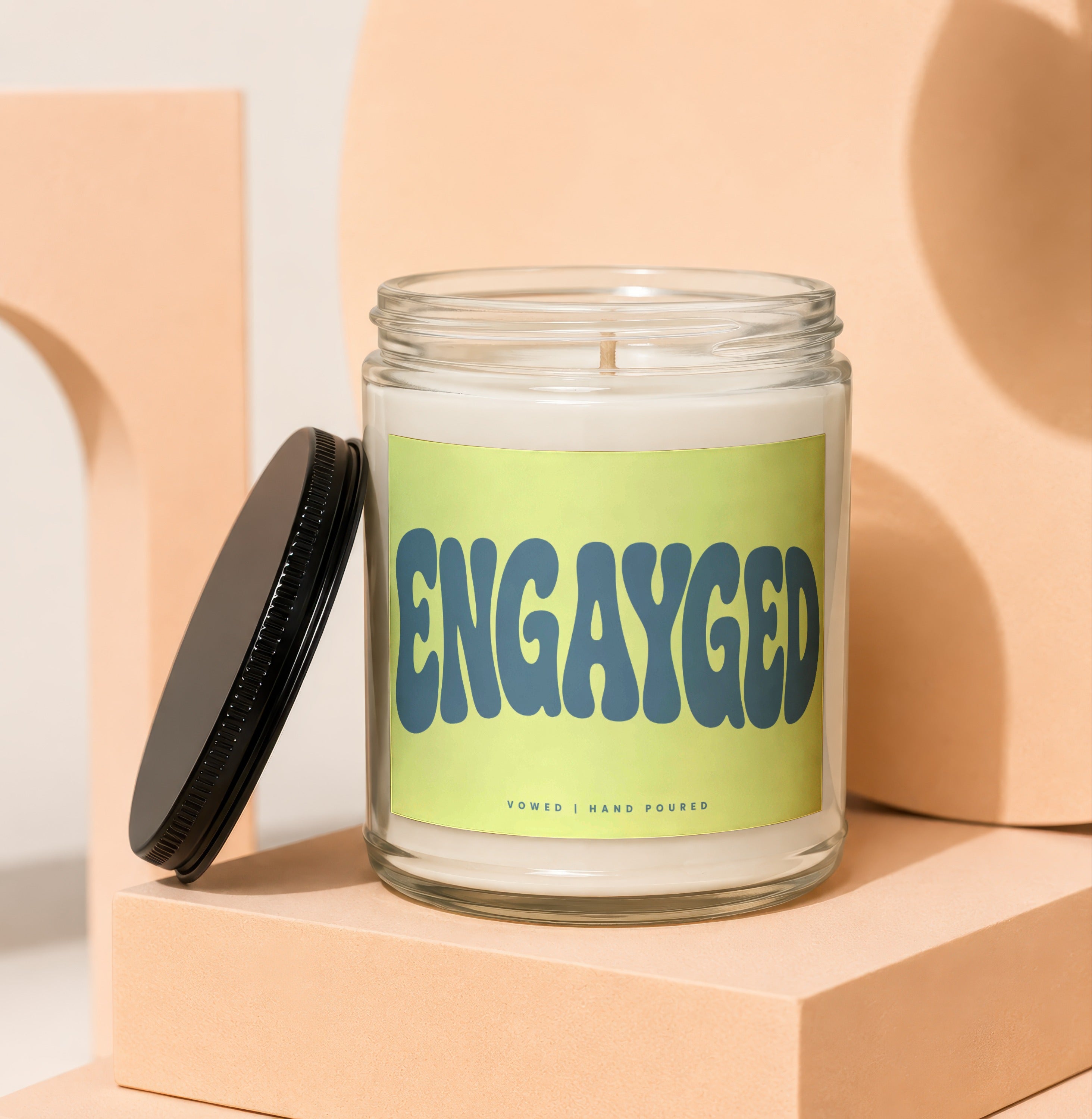 Glass jar candle with "ENGAYGED" text on a light green label.