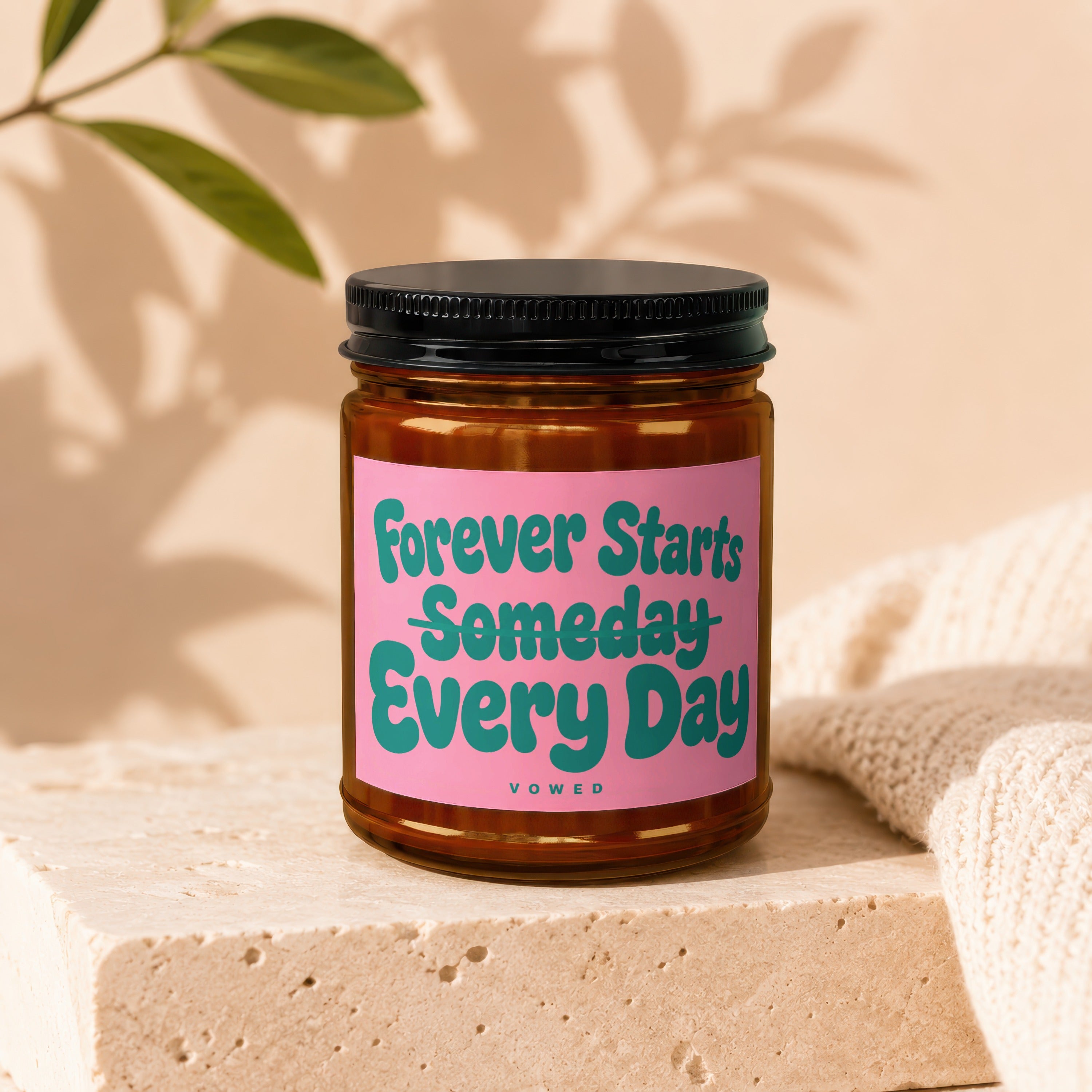 Candle with pink label reading "Forever Starts Someday Every Day" by Vowed.