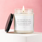 Candle with lit flame and white label reading "May your veil stay put... always have snacks."