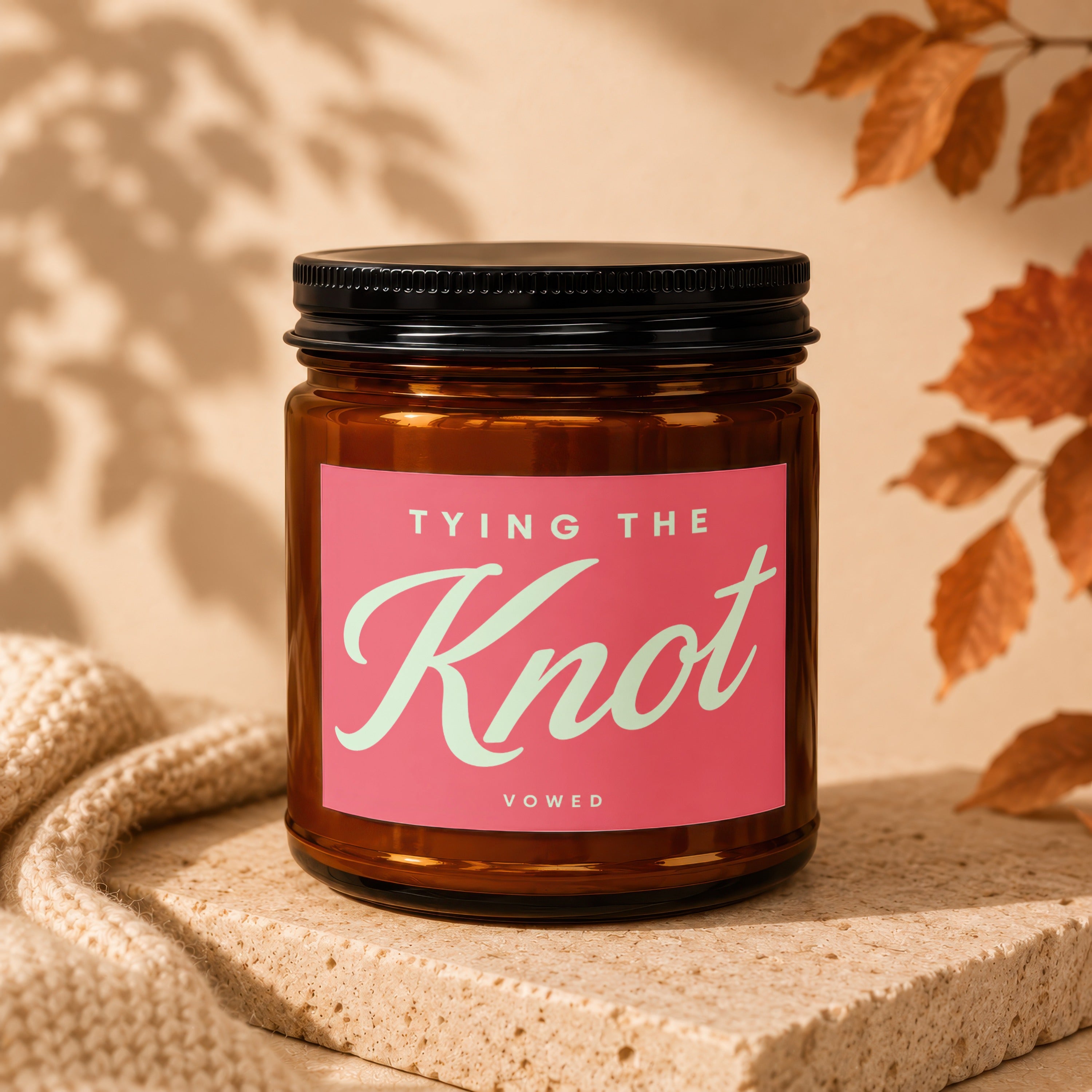 Amber jar candle with pink label reading "TYING THE Knot" and "VOWED".
