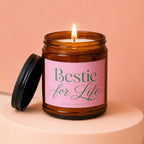 Amber jar candle with burning wick and black lid, labeled "Bestie for Life."
