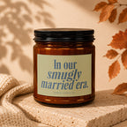 Amber candle with a cream label reading "In our smugly married era. Vowed Candle Co."