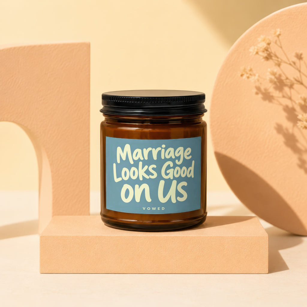 Amber jar candle with blue label that reads "Marriage Looks Good on Us VOWED".