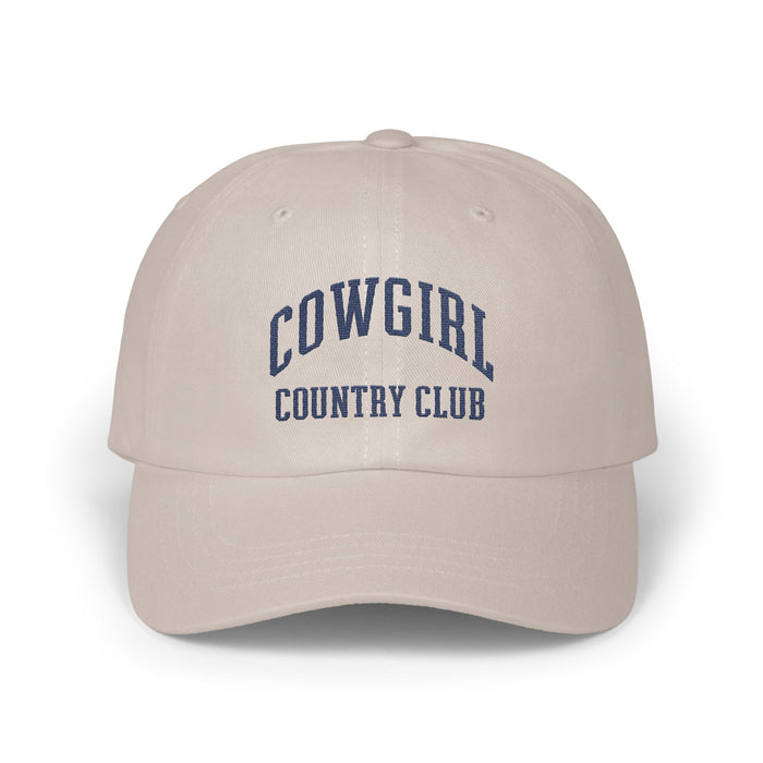 Beige baseball cap featuring blue embroidered text reading COWGIRL COUNTRY CLUB centered on the front panels.