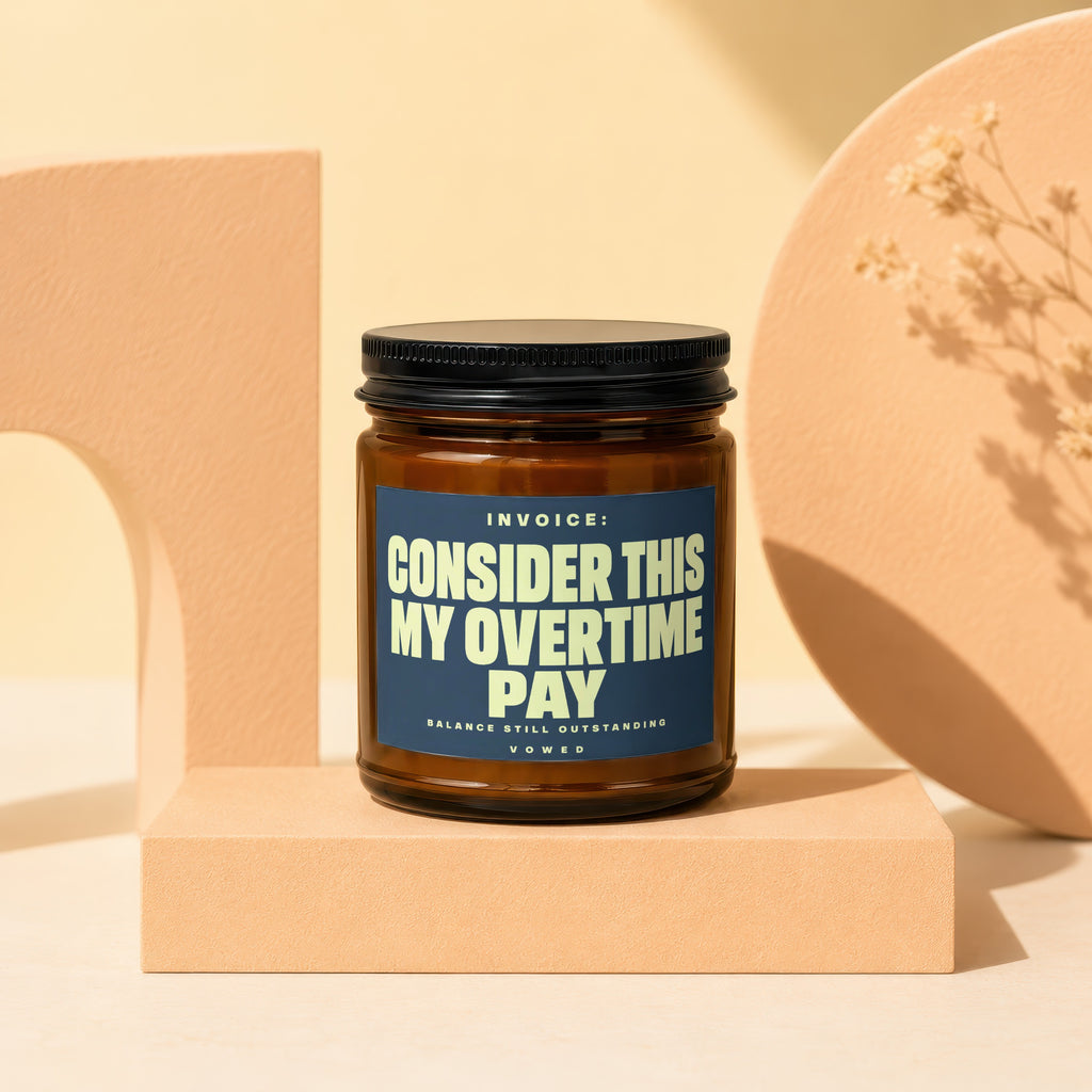 Amber jar candle with black lid and label saying "INVOICE: CONSIDER THIS MY OVERTIME PAY".