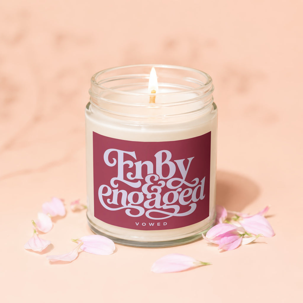 Candle with "Fnby Engaged" and "Vowed" text on maroon label, lit flame.