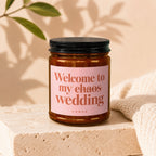 Amber jar candle with pink label reading "Welcome to my chaos wedding."