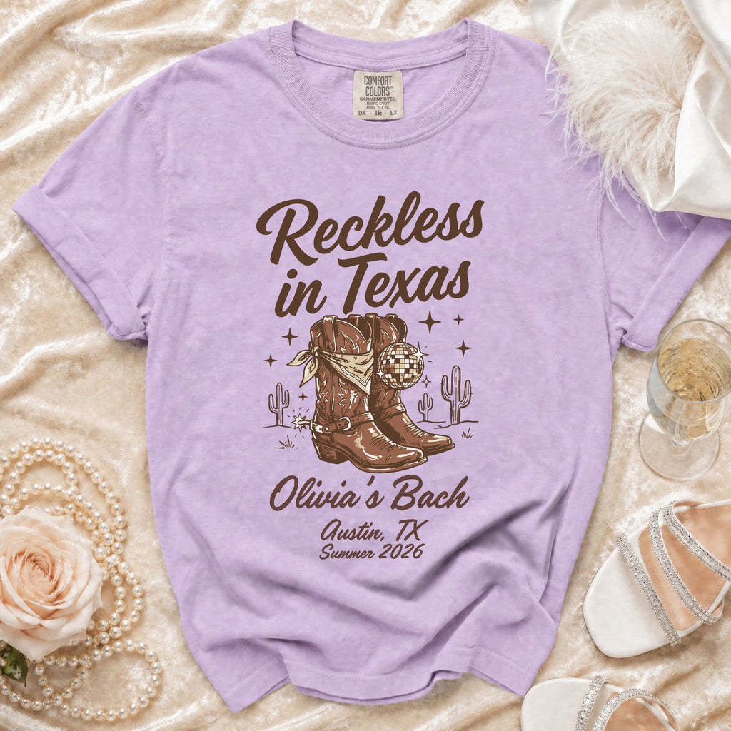 Purple t-shirt with "Reckless in Texas" and cowboy boots graphic.