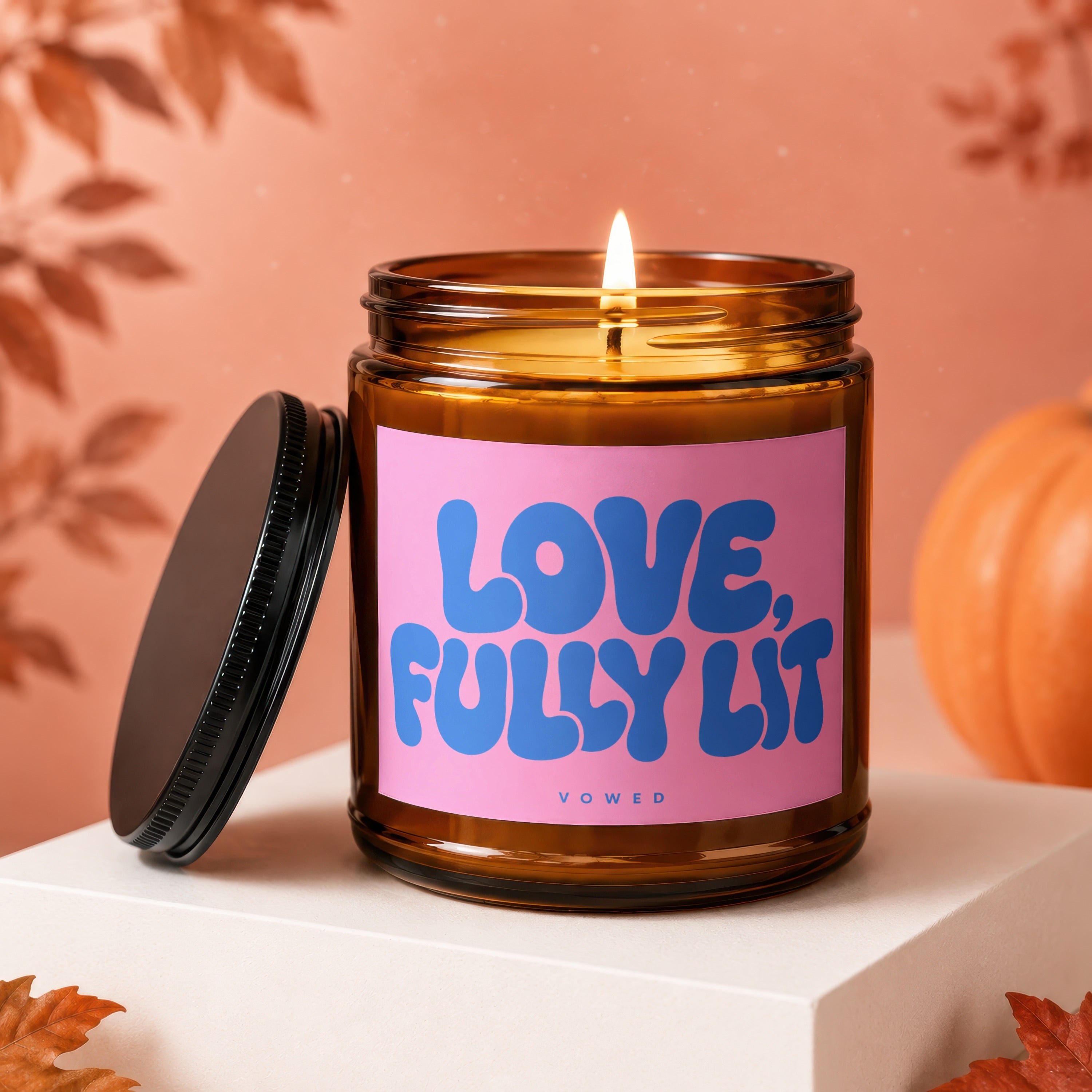 Lit candle in amber jar with pink label reading "Love, Fully Lit"