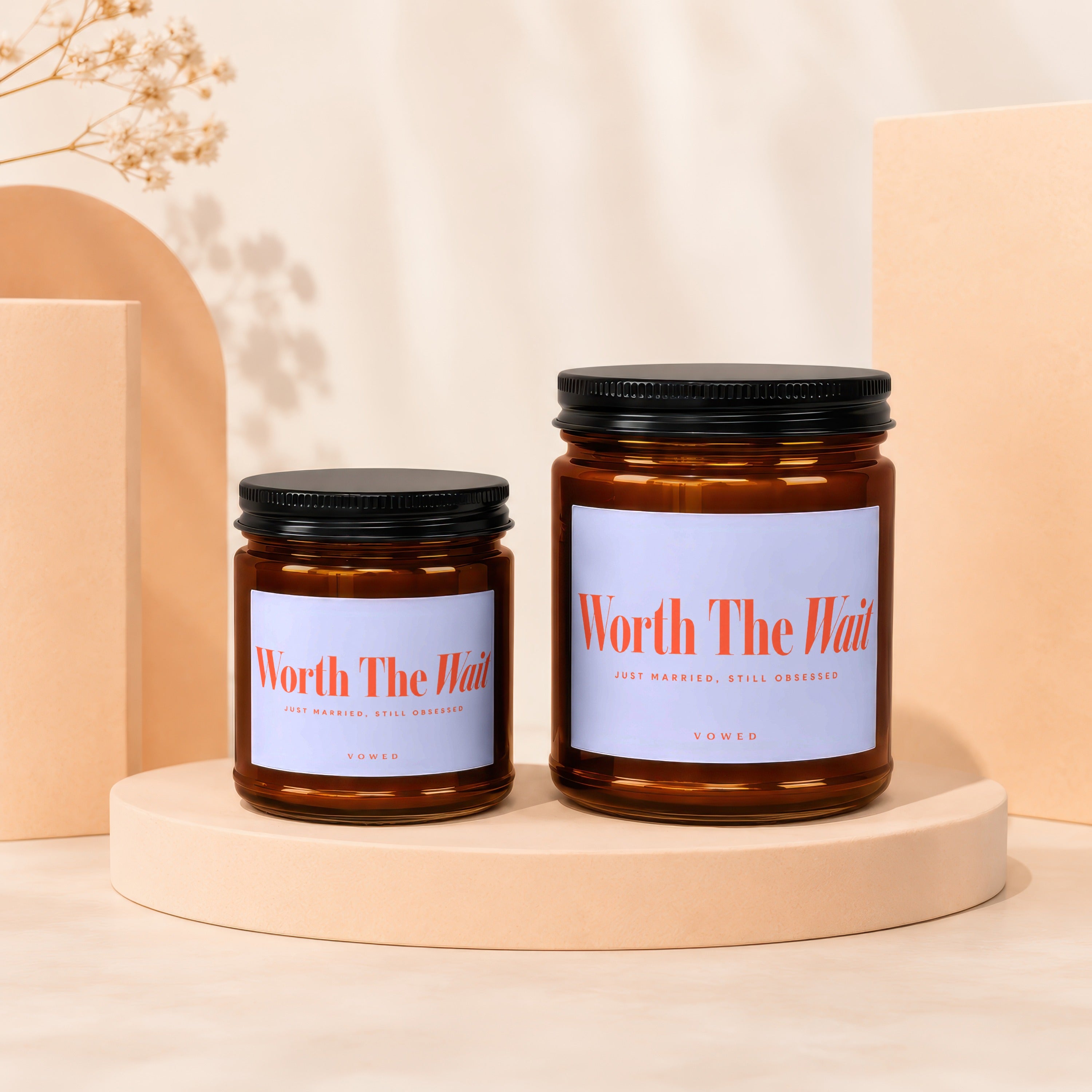 Two amber glass candles with black lids and "Worth The Wait" labels.
