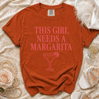 Orange t-shirt with pink text "THIS GIRL NEEDS A MARGARITA" and a margarita glass.