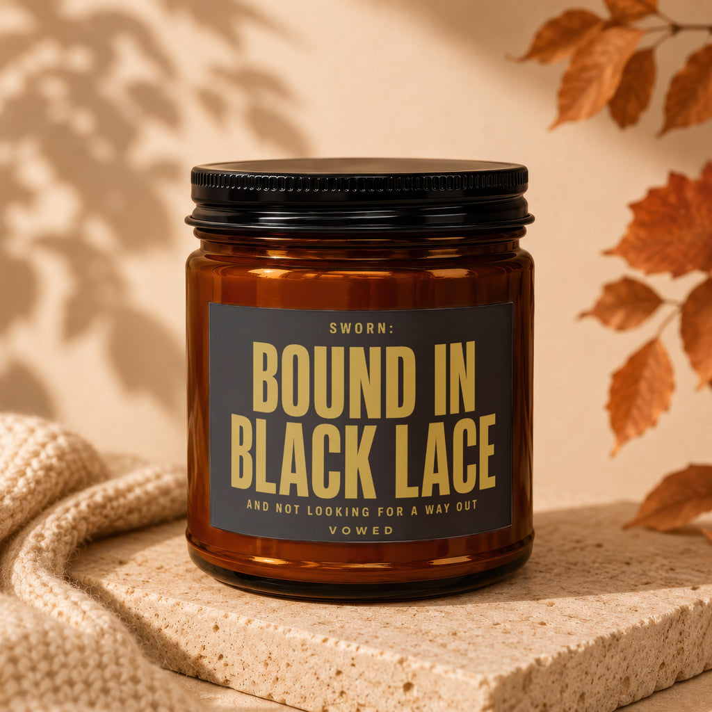 Amber candle with black lid labeled "SWORN: BOUND IN BLACK LACE AND NOT LOOKING FOR A WAY OUT".