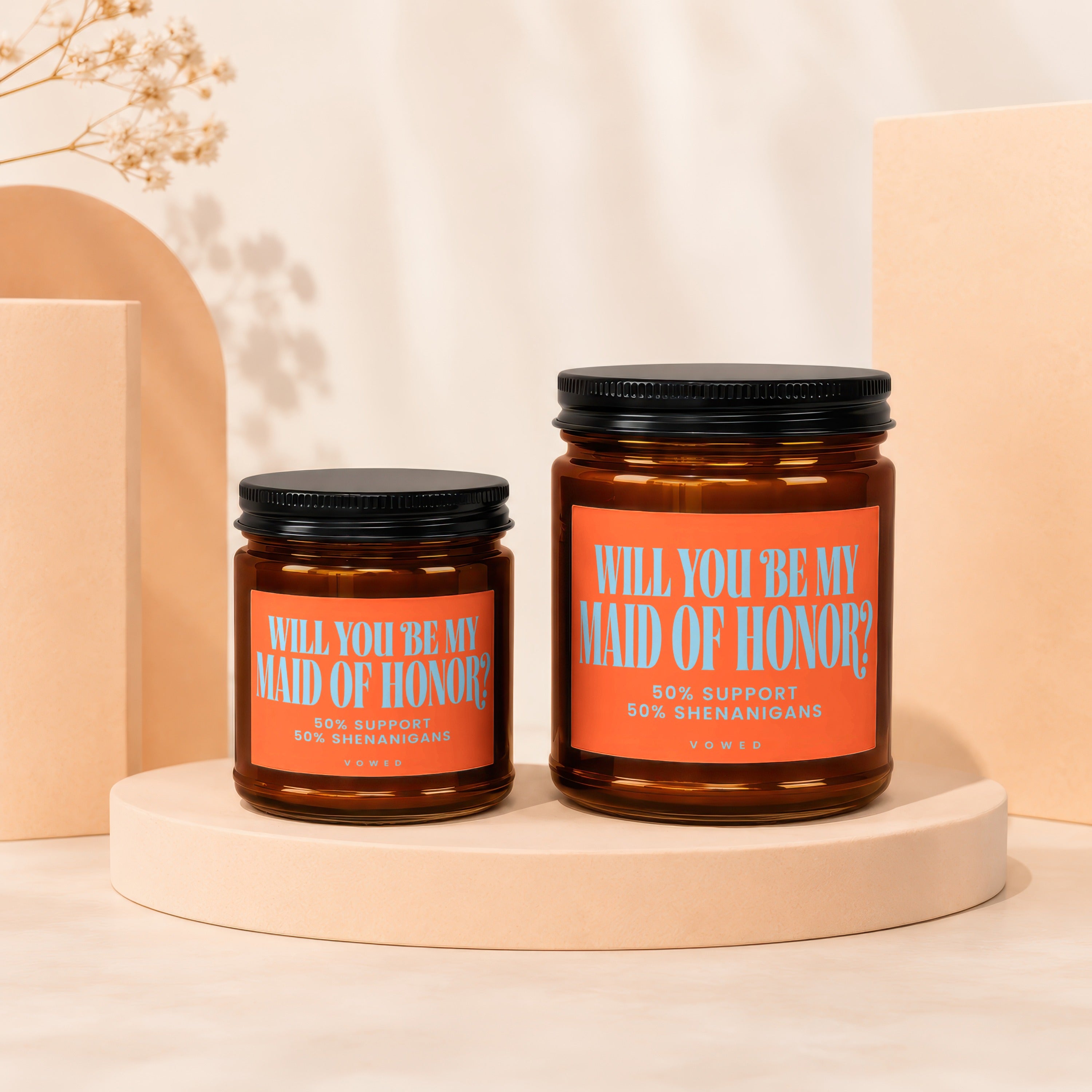 Two amber glass candles with orange labels asking "Will you be my maid of honor?".