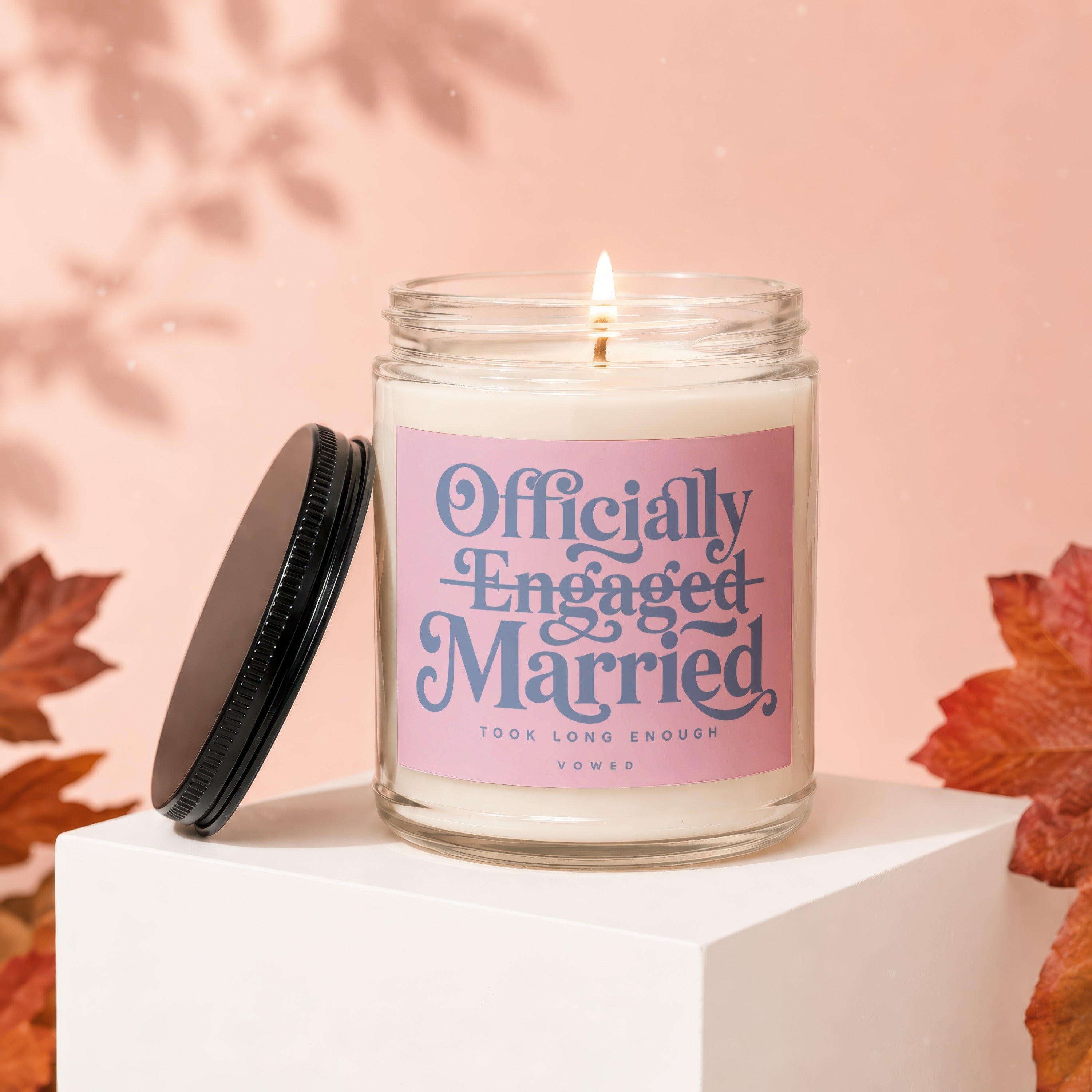 Glass candle with label reading "Officially Engaged & Married, Took Long Enough," lid off.