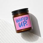 Amber glass jar candle with pink label that reads "WIFED UP."