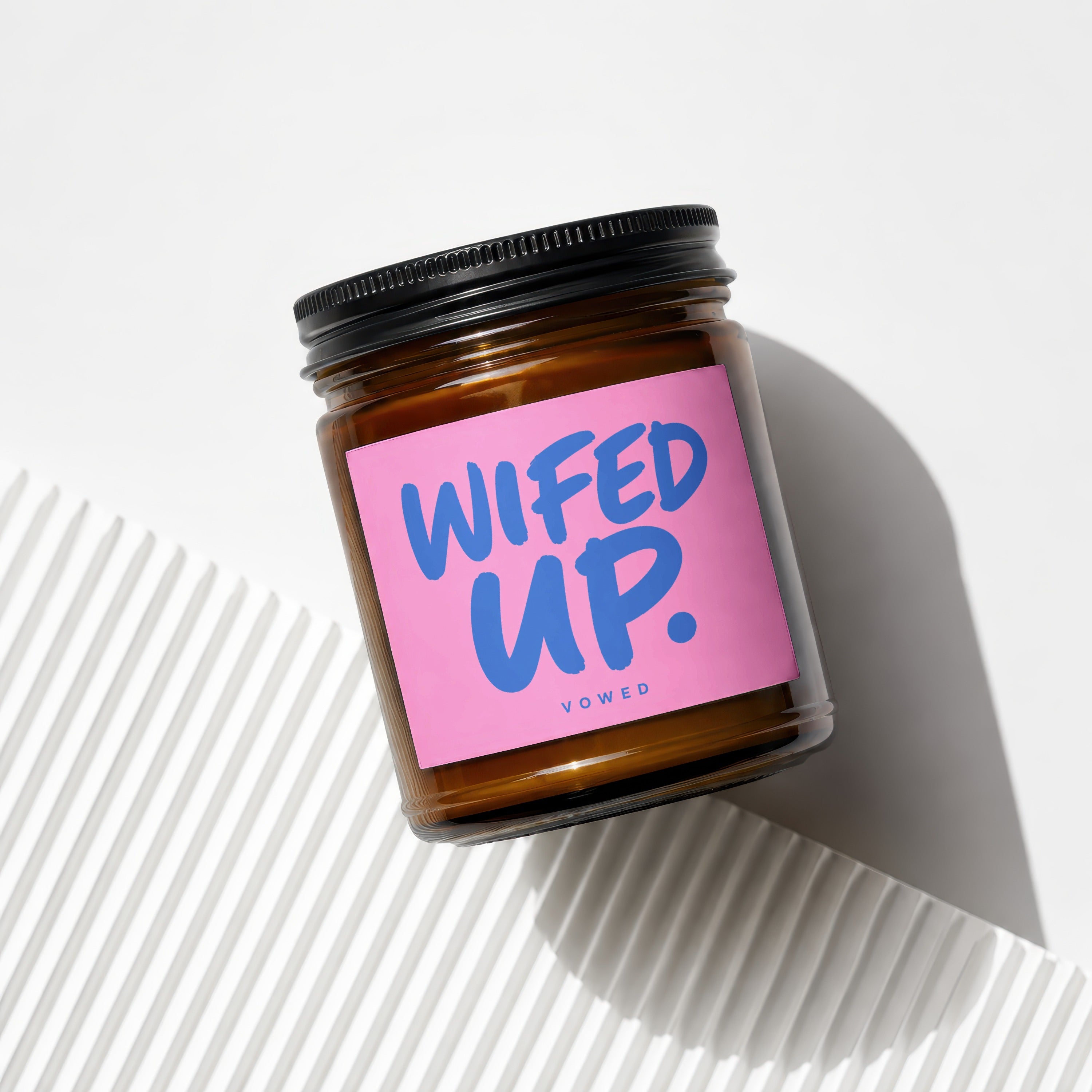 Amber glass jar candle with pink label that reads "WIFED UP."