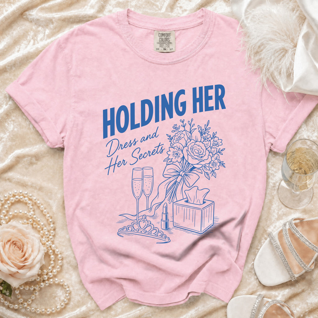 Pink Comfort Colors shirt with blue text "HOLDING HER" and "Dress and Her Secrets" graphic.