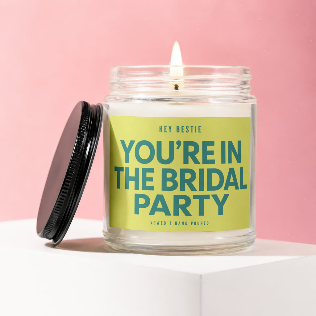 Lit candle in glass jar with bright green label reading "HEY BESTIE YOU'RE IN THE BRIDAL PARTY".