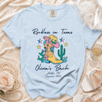 Light blue t-shirt with "Reckless in Texas Olivia's Bach Austin, TX Summer 2026" and boot graphic.