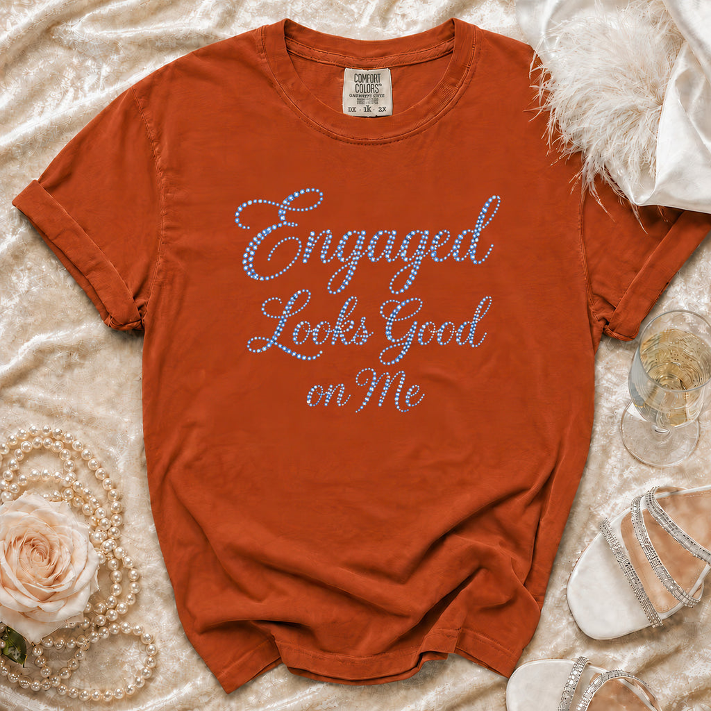 Orange t-shirt with blue rhinestone text "Engaged Looks Good on Me".