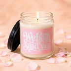 Lit candle in glass jar with pink label saying "We both said yes VOWED".