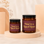 Two amber glass candles with black lids; labels read "You're a Man of Honor".