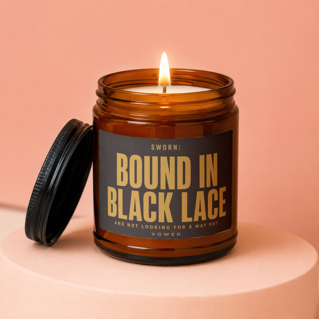 Amber jar candle with lid off, lit flame, and text "SWORN: BOUND IN BLACK LACE".