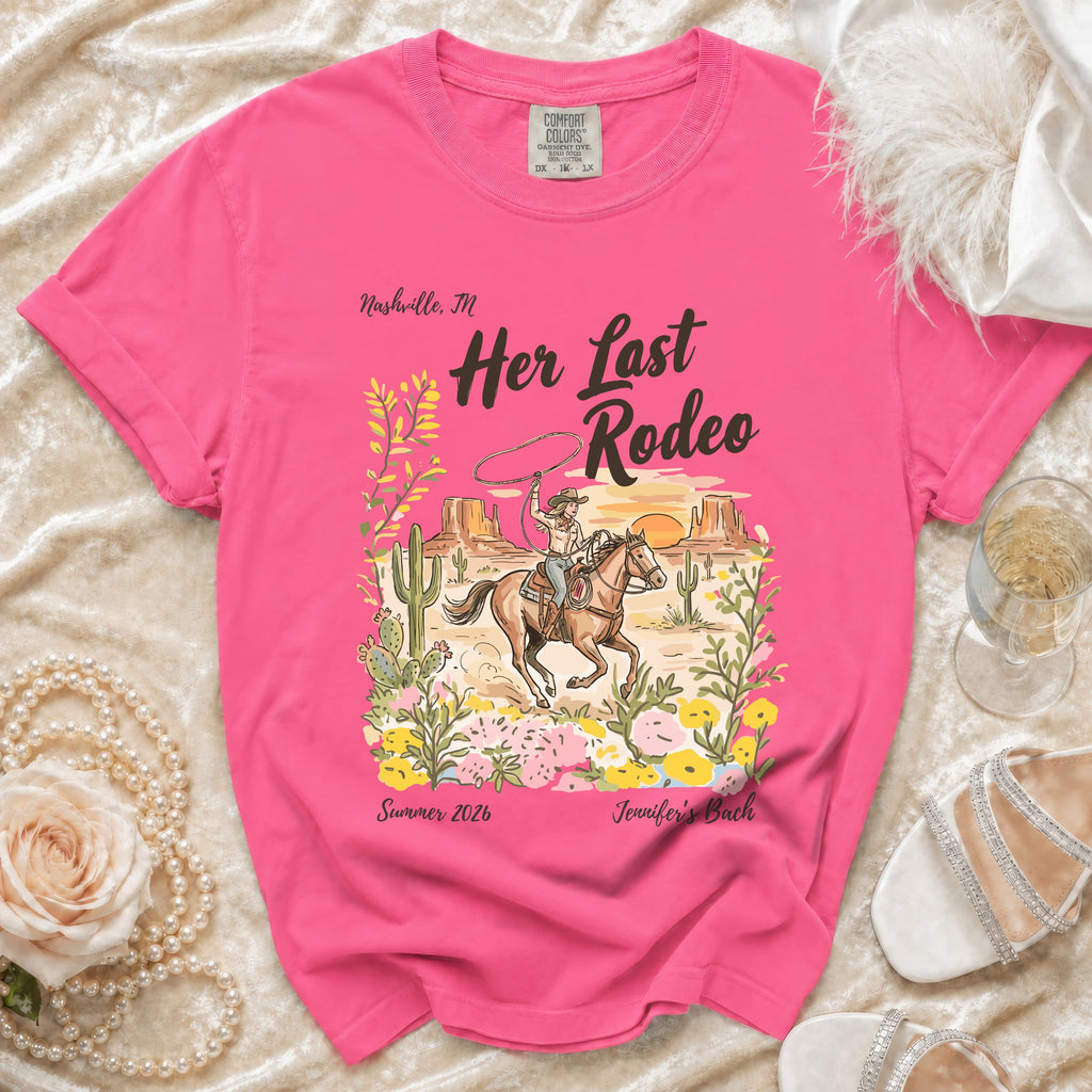 Pink t-shirt with "Her Last Rodeo" graphic, cowboy on horse, cactus, flowers, and text.