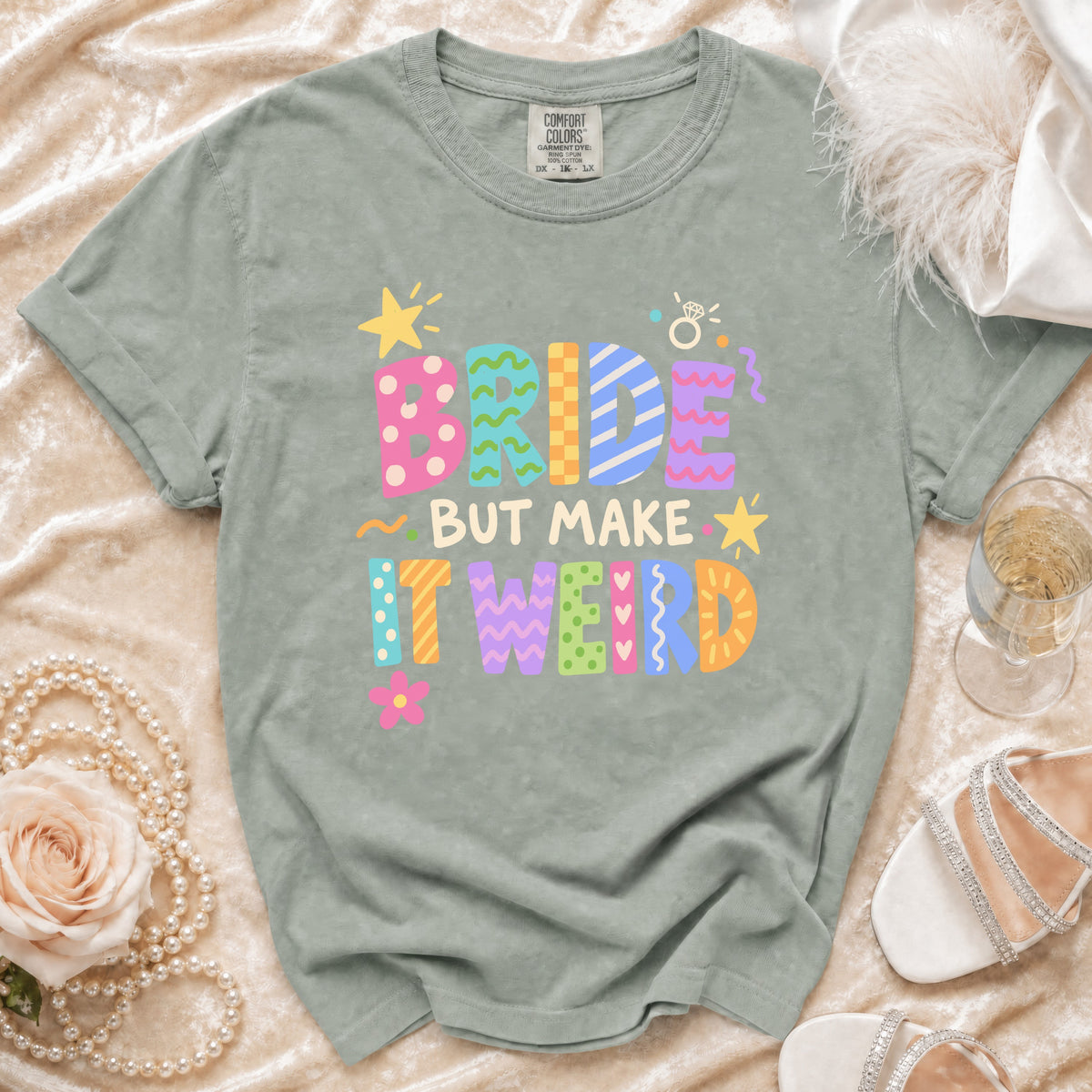 Green t-shirt with "BRIDE BUT MAKE IT WEIRD" graphic in colorful block letters.