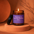 Amber glass candle with purple label reading "Welcome to Your Pre-Wedding Era."