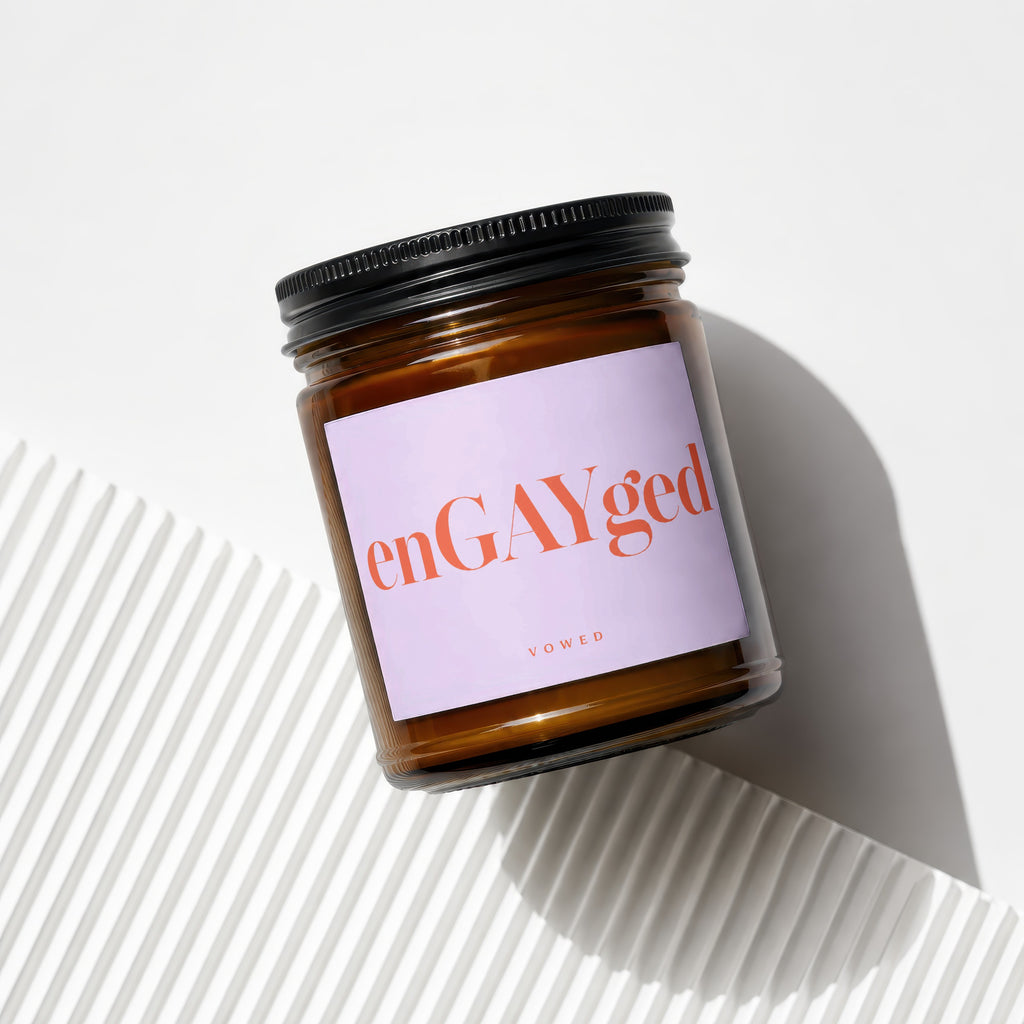 Amber jar candle with text "enGAYged" and "vowed" on a light purple label.