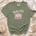 Green t-shirt with "lucky in love" and "JUST MARRIED" slogan, featuring a slot machine graphic.