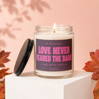 Candle with text "Love Never Feared the Dark" and flaming wick on display.